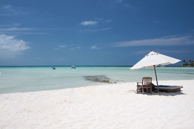 A sunny summer morning on the beautiful white sand beach with a chaise lounge and umbrella 