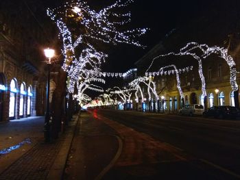 Illuminated road in city against sky at night