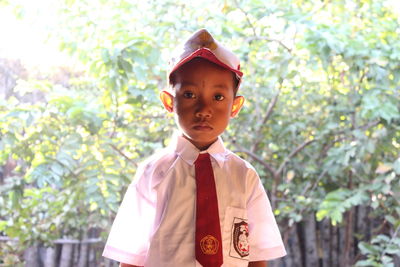 Portrait of boy standing against trees