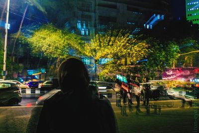 Woman walking on illuminated city street at night