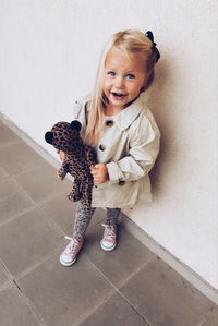 Portrait of smiling girl standing against wall