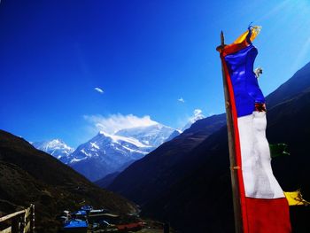 Panoramic view of flag on mountain against blue sky