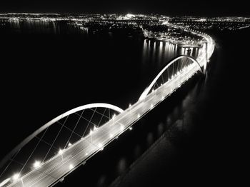 Illuminated bridge over river in city at night