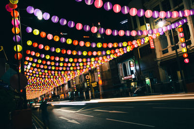 Illuminated road amidst buildings in city at night