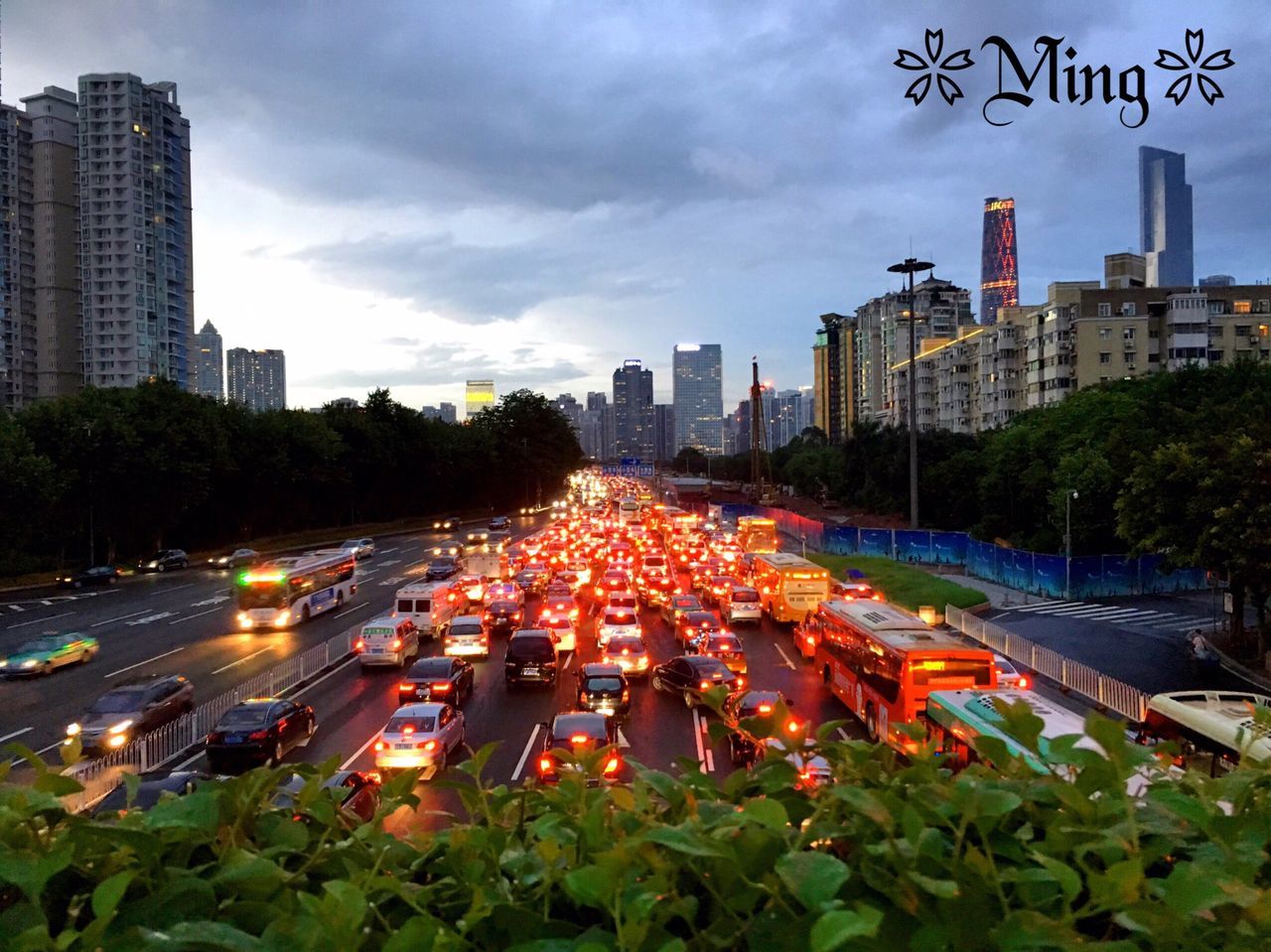 building exterior, city, architecture, built structure, sky, street, transportation, car, city life, road, tree, skyscraper, city street, cloud - sky, building, cityscape, land vehicle, growth, high angle view, traffic