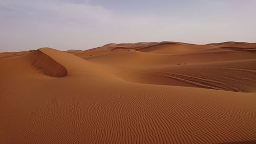 Sand dunes in desert against sky