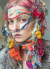 Close-up portrait of woman with colorful threads on face