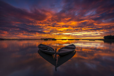 Boat in lake against sky during sunset