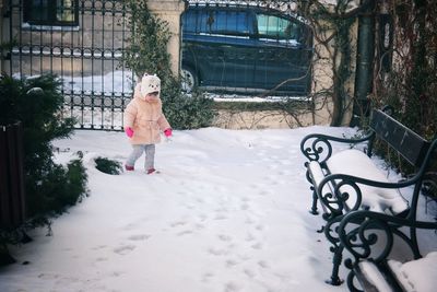 Preschool girl walking on snow covered footpath at park