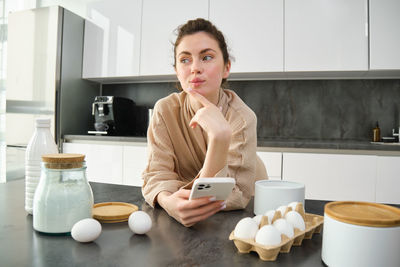 Portrait of young woman having food at home