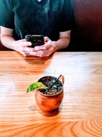 Midsection of woman photographing with mobile phone on table