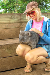 Full length of woman with wombat sitting outdoors