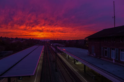 Railroad station platform against sky at sunset