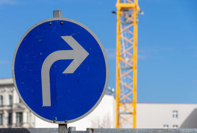 Low angle view of road sign against blue sky