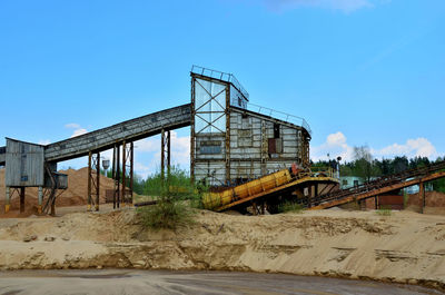 Low angle view of abandoned factory against clear blue sky