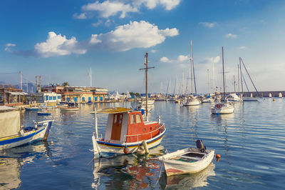 Sailboats moored at harbor against sky