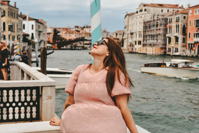 Portrait of young woman standing against buildings