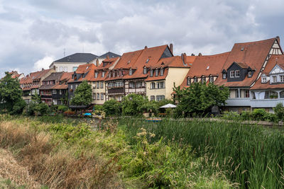 Houses by buildings against sky