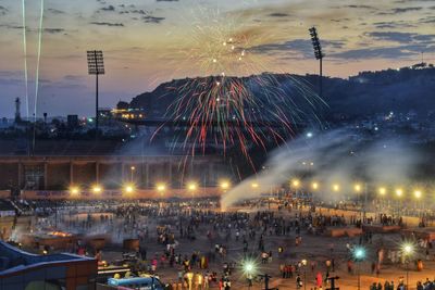 Firework exploding over crowd at town square in city during sunset