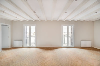 Empty and clean room in a refurbished apartment with wooden floor and two balconies