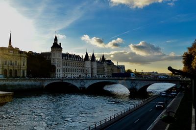 Arch bridge over river against sky in city