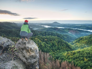 Hiker man take a rest on peak. traveler with green windproof jacket resting on the mountain peaks