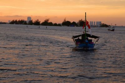 Boat sailing in sea against sky during sunset