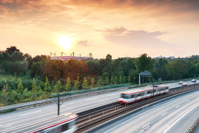 Blurred motion of vehicles on road against sky during sunset