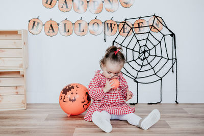 Beautiful one year old caucasian girl at home with halloween decoration, lifestyle indoors.