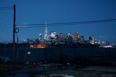 Illuminated buildings in city against sky during winter