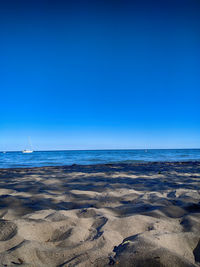 Scenic view of beach against clear blue sky