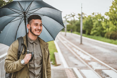 Man with umbrella  on a rainy day. handsome young tourist with backpack is crossing the road