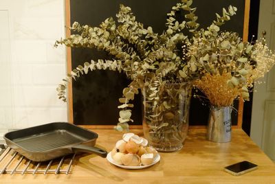 Eggshells and frying pan with mobile phone by vases on table