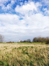 Scenic view of grassy field against cloudy sky