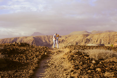 Rear view of man walking on field against sky