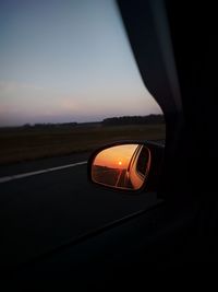 Close-up of car on road against sunset sky