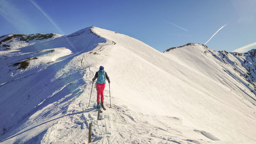 Woman tour skiing on snow crapped mountain