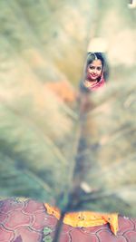 Portrait of young woman with umbrella on leaves