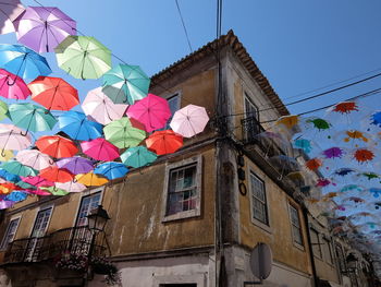 Low angle view of colorful umbrellas hanging against building