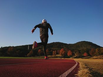 Full length of man running against clear blue sky