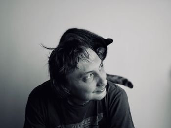 Man with cat on shoulder against wall at home