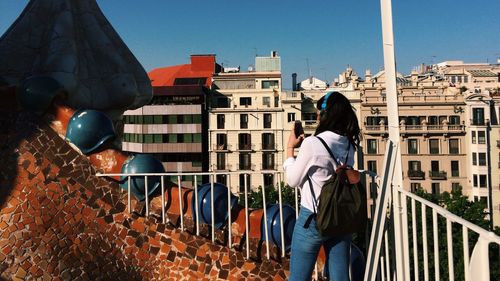 Woman standing by railing against buildings in city