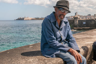 Man sitting by sea against sky