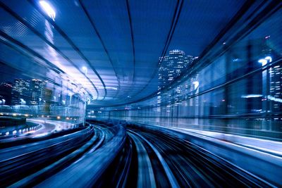 Blurred motion of illuminated railroad tracks in city at night