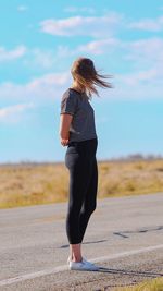 Rear view of woman standing on road against sky