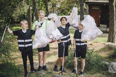 Full length portrait of smiling male volunteers holding garbage bags