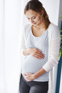 Pregnant woman touching belly at home