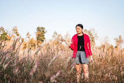 Portrait of woman standing on field against sky