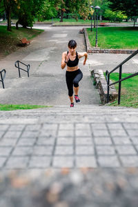 Full length of young woman running on footpath