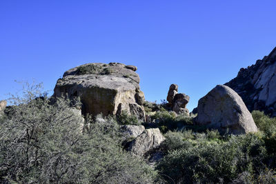 Low angle view of rock formation against clear blue sky